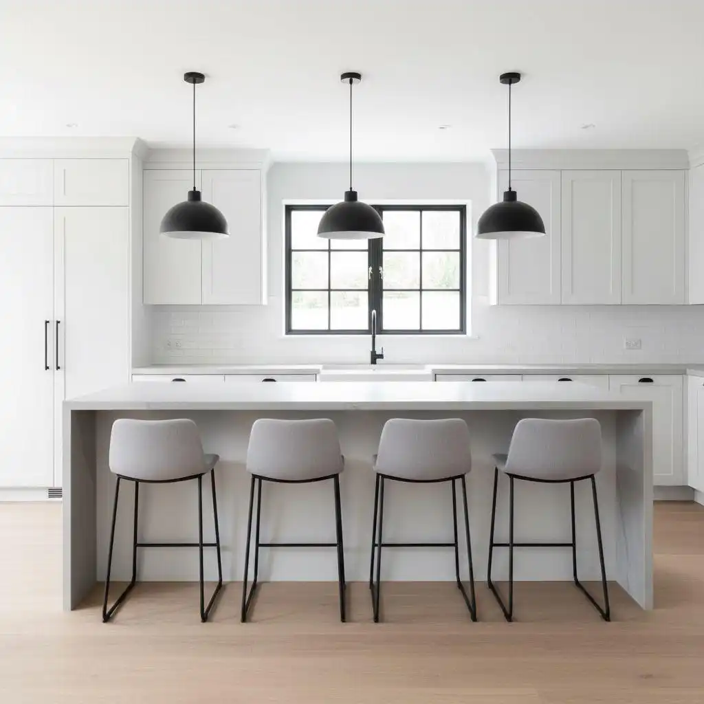 Minimalist white kitchen featuring a rectangular small kitchen island with a waterfall countertop and seating for four gray modern bar stools, framed by three black pendant lights.