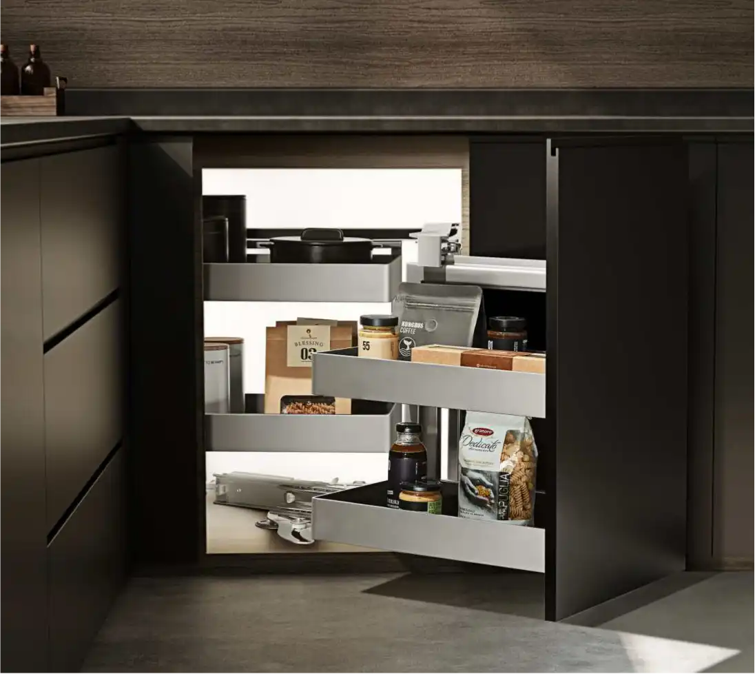 L shaped kitchen corner solutions 5 A two-tier dark grey LeMans-style swivel organizer inside a black L-shaped corner cabinet, holding a black pot, white ceramic jar, and various spice containers.