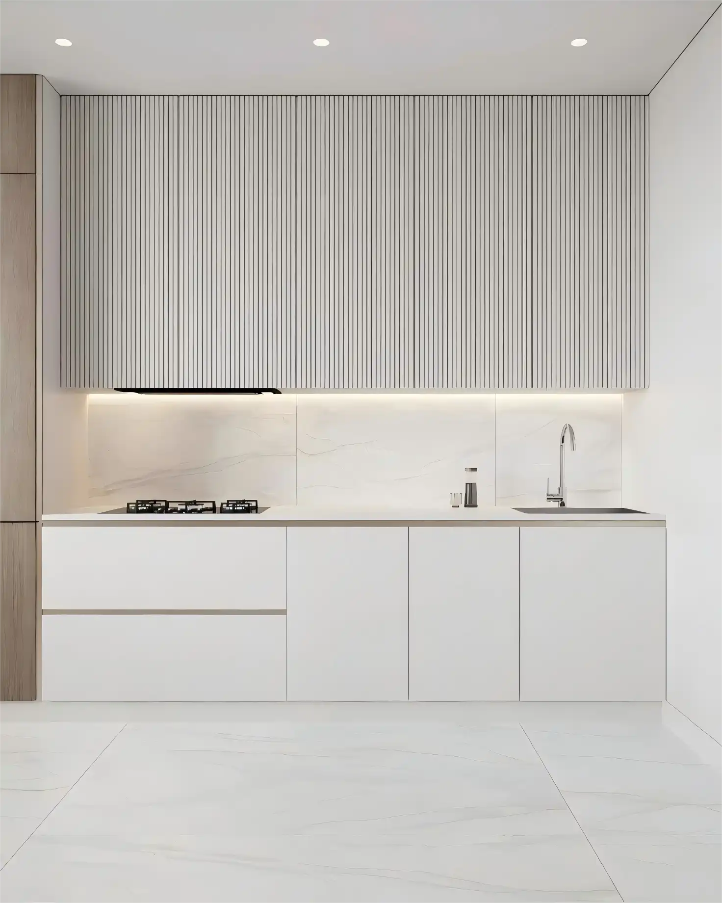 Minimalist kitchen with floor-to-ceiling white fluted kitchen cabinets over a white countertop, featuring an integrated gas cooktop and chrome faucet.