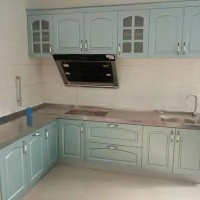 U-Shaped Kitchen Featuring Light Aqua Blue Cabinets in a Traditional Style with Glass Inserts, Stainless Steel Countertops, and a Modern Range Hood.