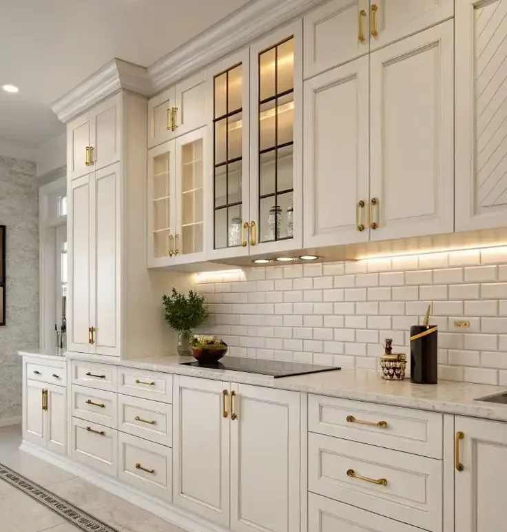 Elegant American kitchen cabinet design with off-white raised panel doors, gold hardware, and glass-front upper cabinets.