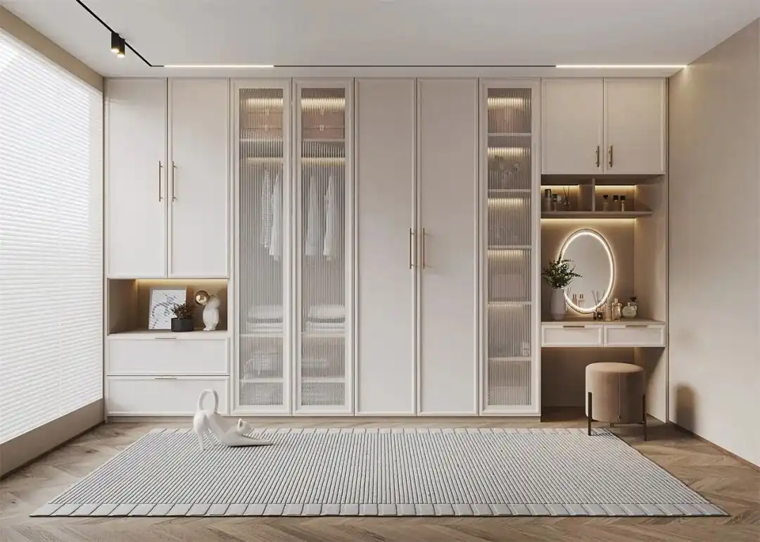 Custom Wardrobe Design 7 Cream-colored custom wardrobe design featuring reeded glass door panels, gold handles, and an integrated dressing table with a velvet stool.