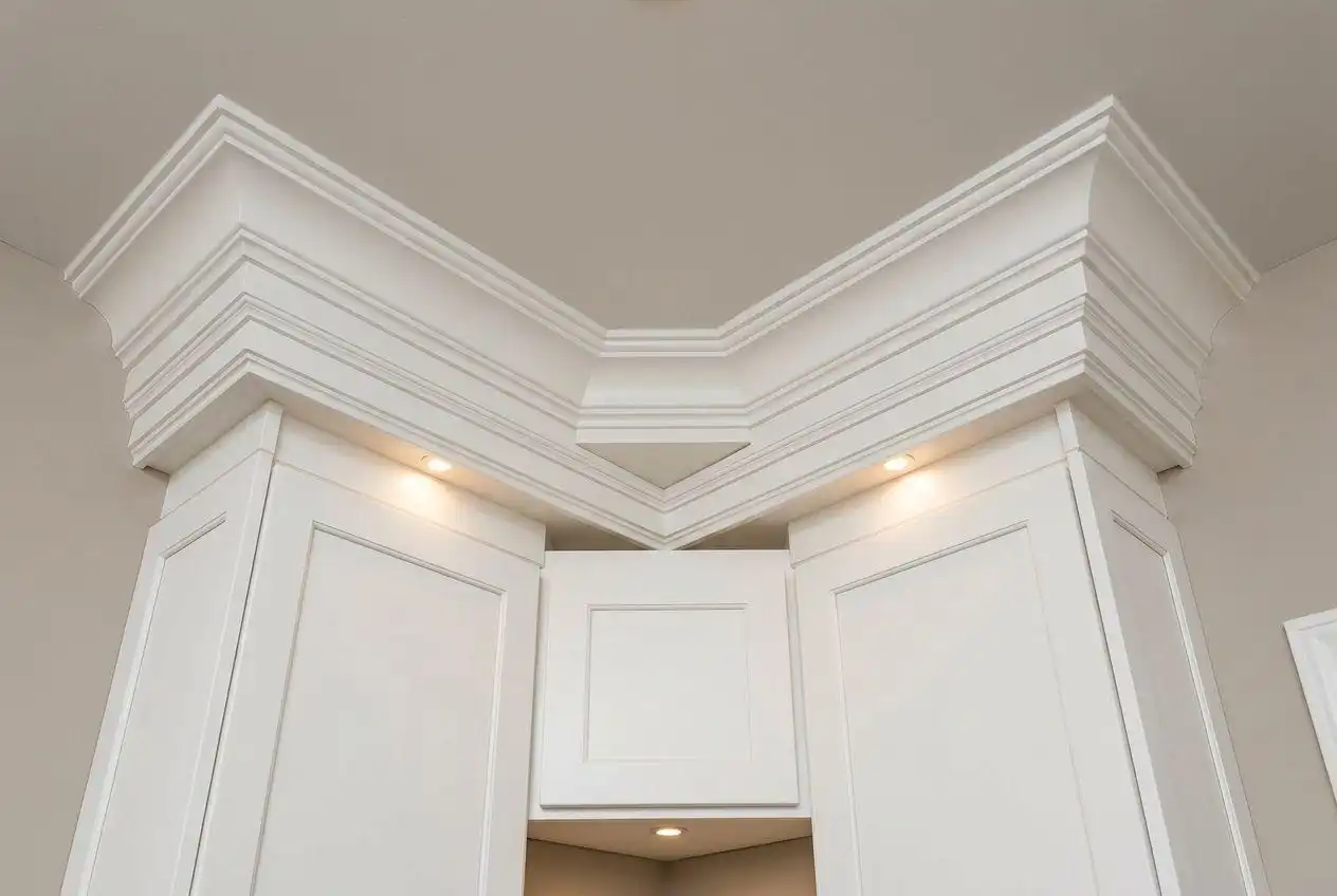 White shaker-style wall corner kitchen cabinet with integrated spotlights and elaborate multi-tier crown molding.